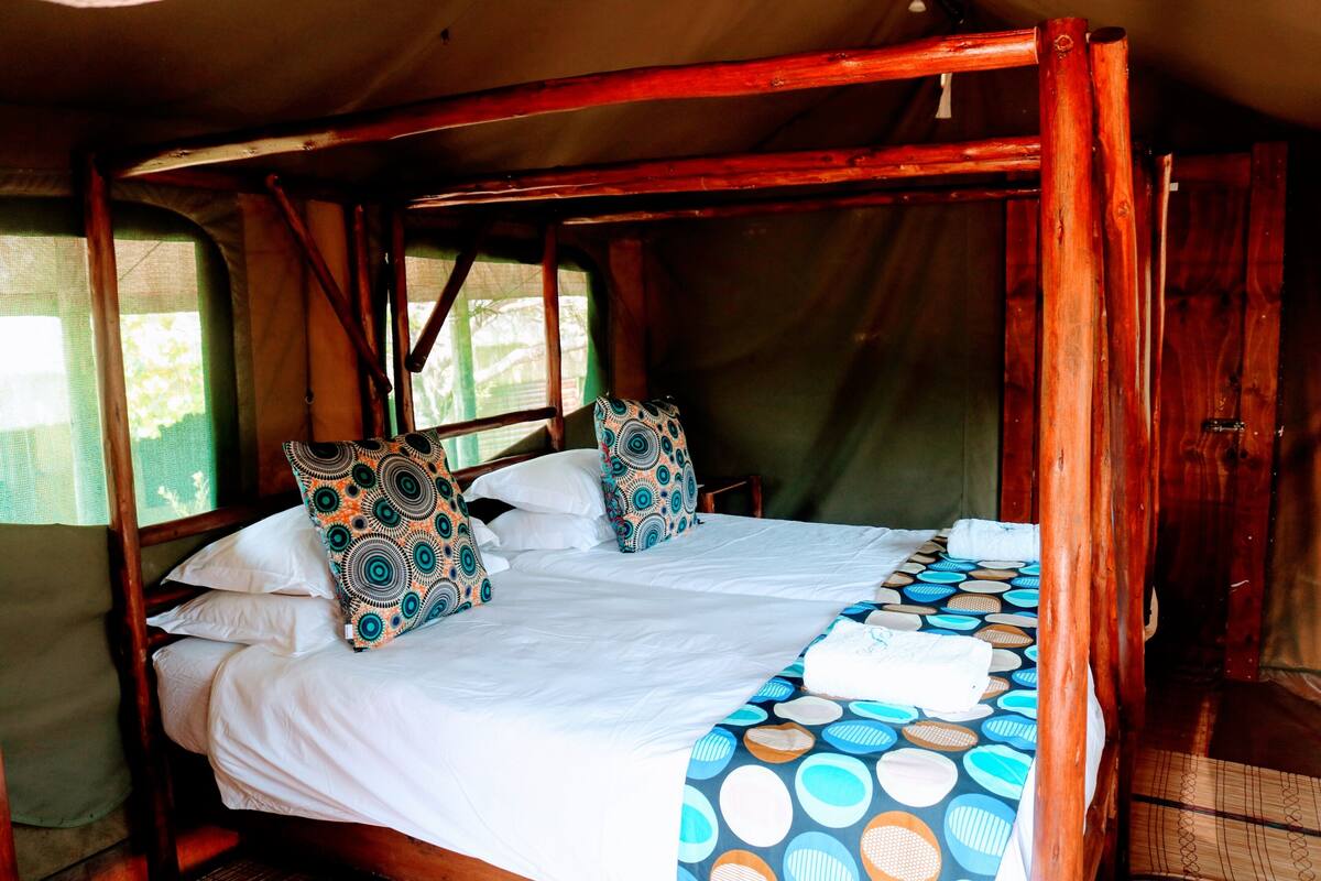 A single bed with a patterned bedspread, two pillows with a circular design, and a wooden headboard.