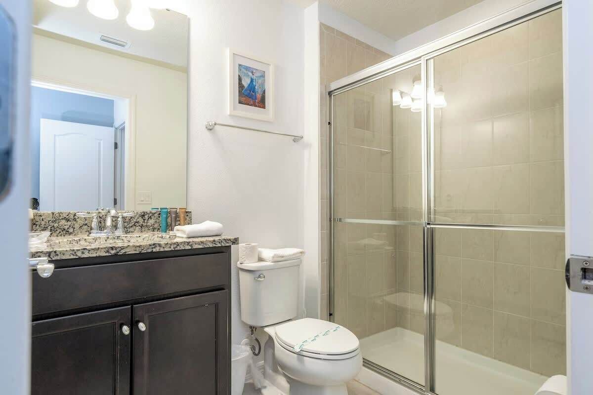 A bathroom with a toilet, sink, and shower area.