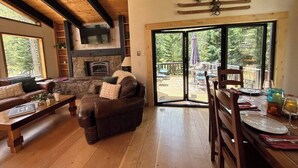 A cozy living room with a fireplace, wooden furniture, and a dining area with a view of the outdoors. - 4-bedroom house with Hottub in charming Breckenridge (Breckenridge)