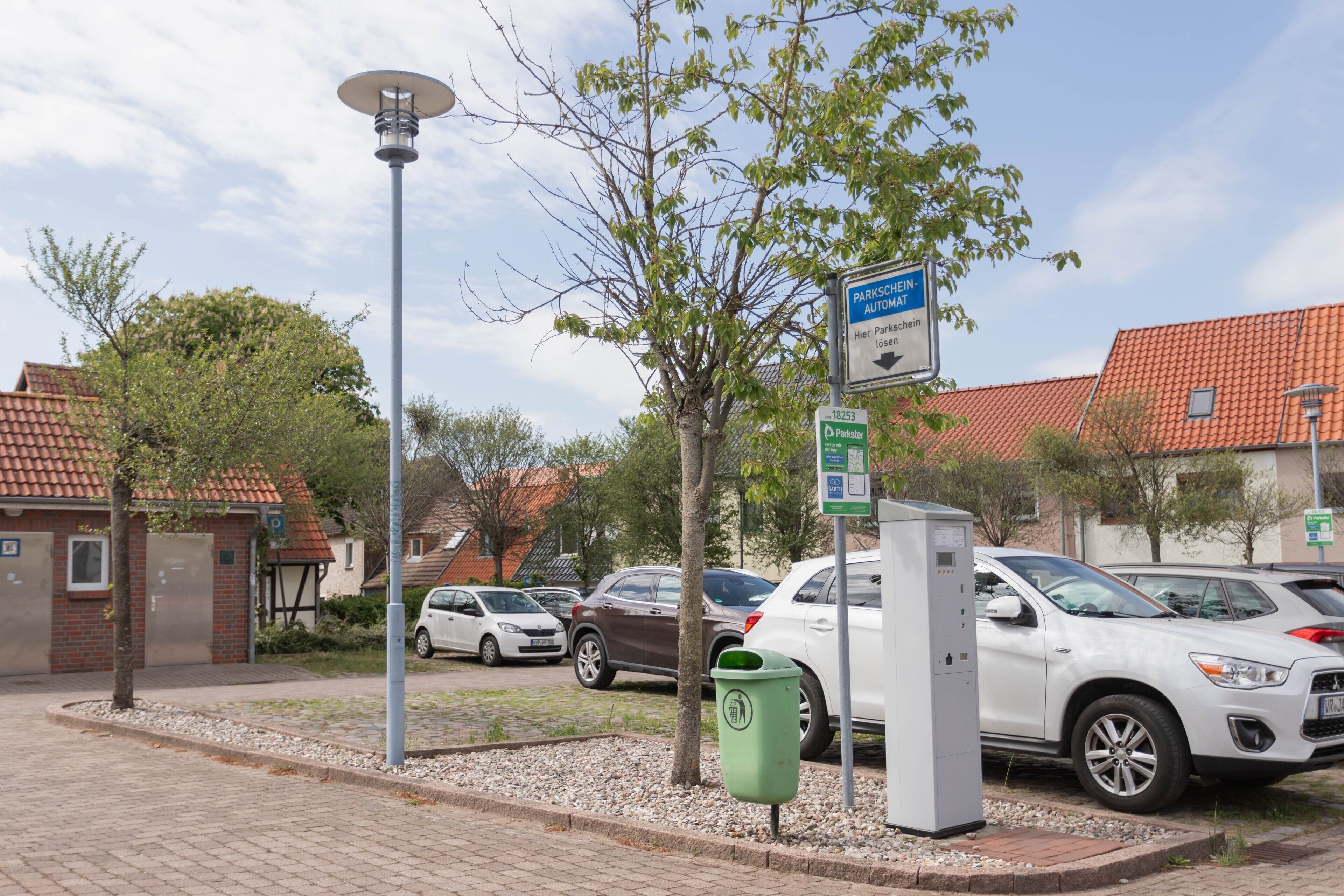 Un espace de stationnement avec un panneau indiquant « automate de paiement pour le stationnement » et un lampadaire solaire.