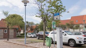 Un espace de stationnement avec un panneau indiquant « automate de paiement pour le stationnement » et un lampadaire solaire.