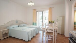 Ein Schlafzimmer mit zwei Betten, einem Esstisch und einer Küchenzeile.