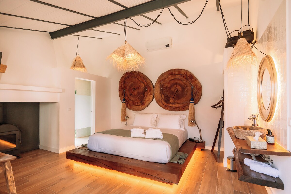 A modern bedroom with a wooden platform bed, a built-in bench, a large mirror, and a wooden headboard.