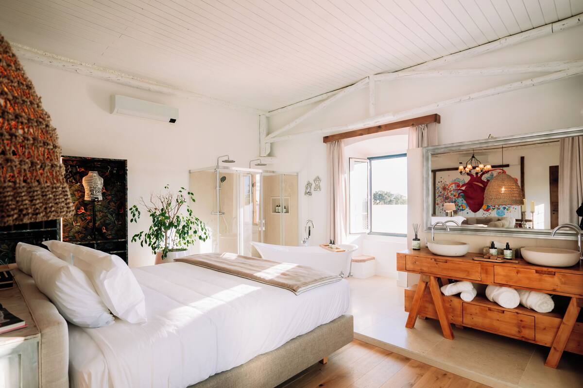 Un dormitorio con una cama grande, un tocador de madera con espejo y una bañera.