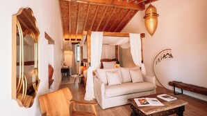 A cozy room with a wooden ceiling, a white sofa, a wooden chair, a small table with magazines, and a large mirror. - Herdade dos Moreiros (Arronches)