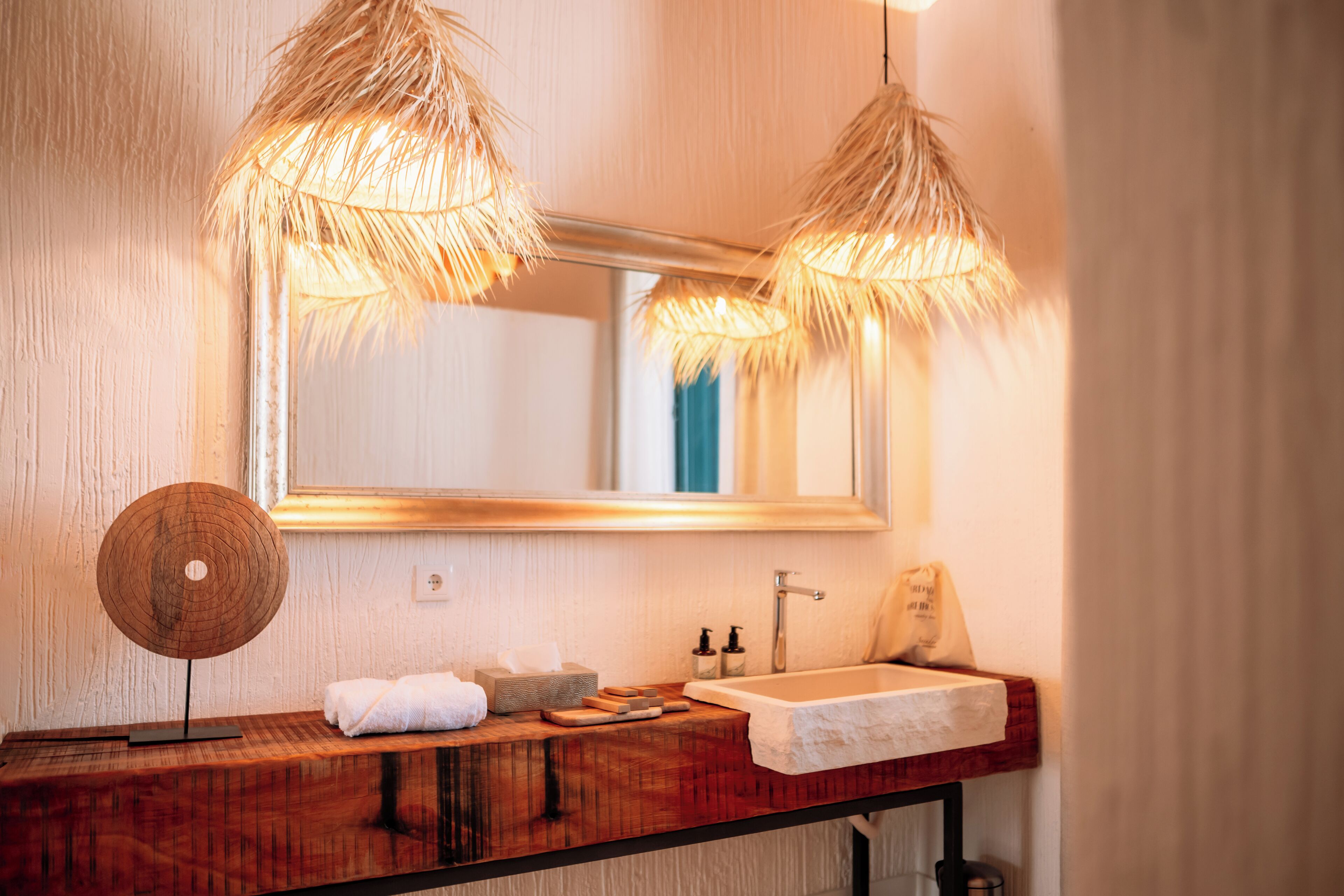 Un baño con tocador de madera, un espejo grande y dos lámparas colgantes.