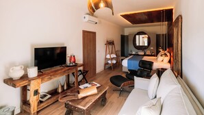 A compact hotel room with a wooden desk, a sofa, a bed, and a TV. - Herdade dos Moreiros (Arronches)