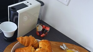 Aamiaistarjotin, jossa on croissantteja, kuppi ja lasit täynnä appelsiinimehua, puisella pöydällä.