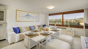 En matplats med ett bord för fyra personer, en soffa och ett stort fönster med utsikt.