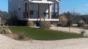 Une maison moderne à deux étages, dotée d’un porche abrité, d’une petite terrasse et d’une allée gravillonnée.
