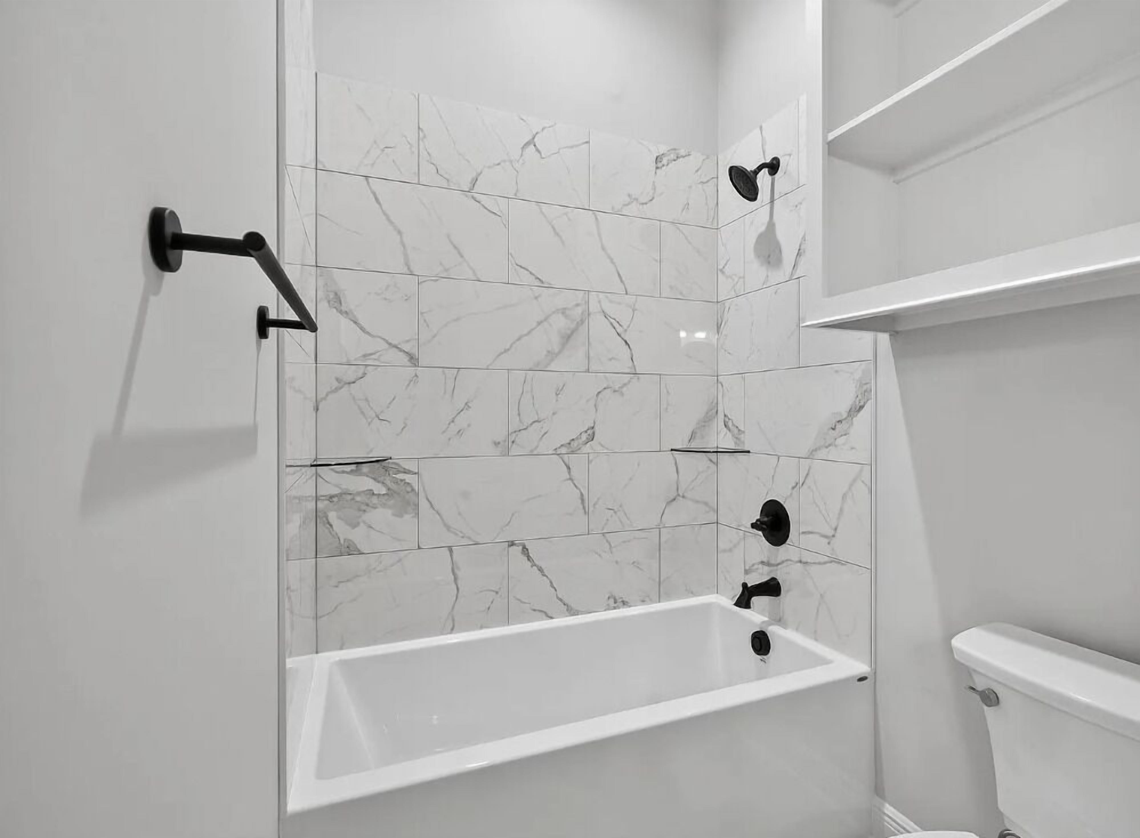 Een moderne badkamer met een vrijstaand bad, een douchekop en een toilet.