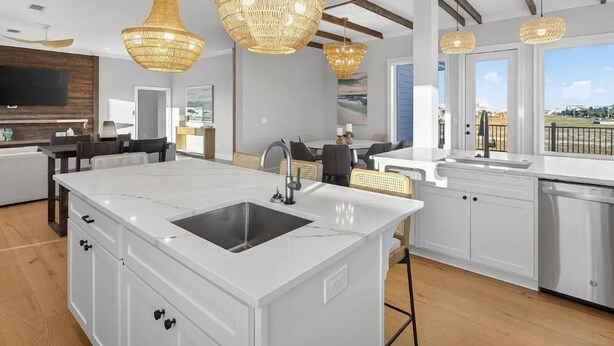 A modern kitchen with a central island, white cabinetry, and a large window offering a view. - Salt Water Heals Everything (Gulf Shores)