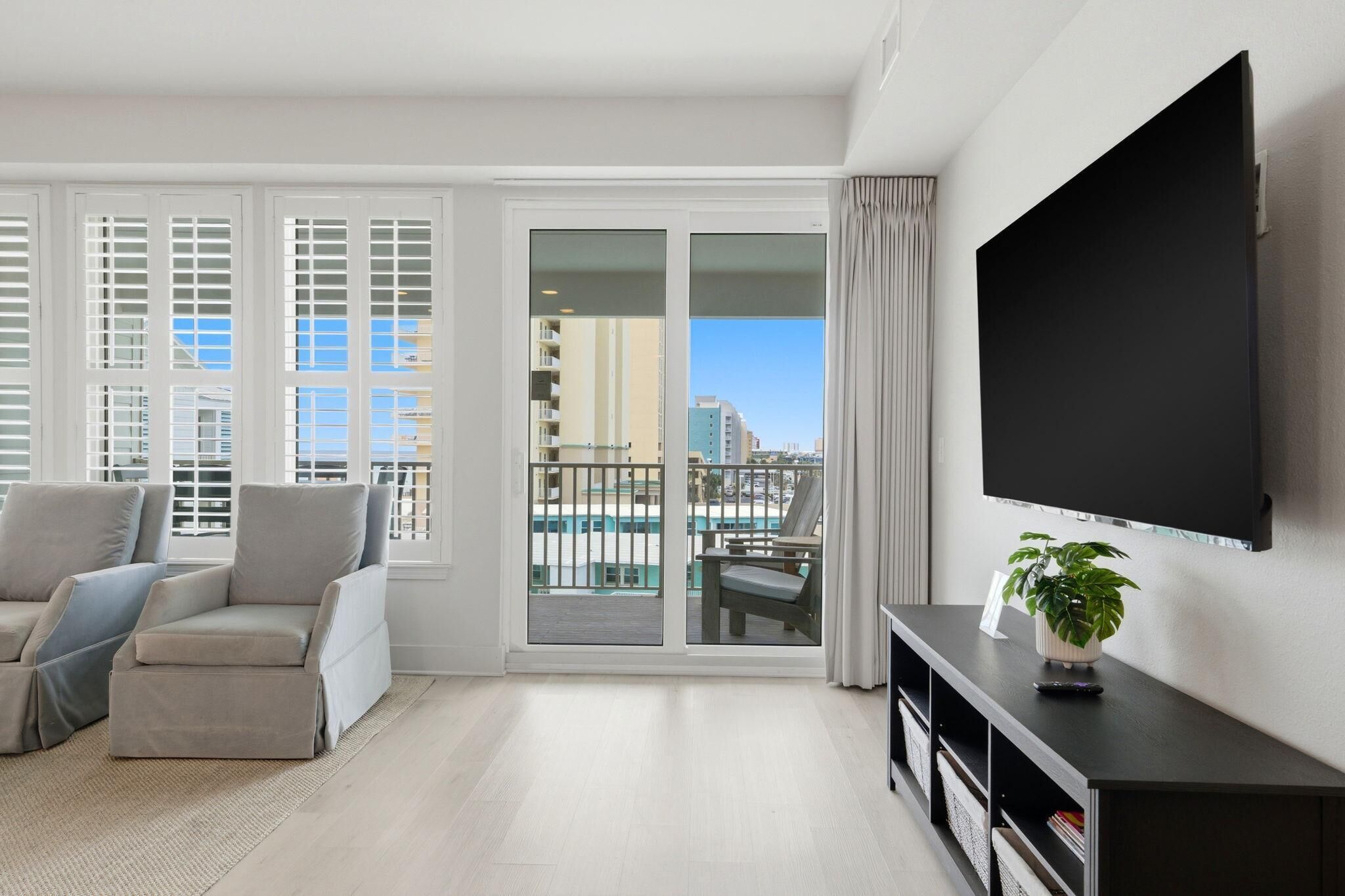 Un soggiorno moderno con una grande TV, un divano, un tavolo da pranzo e un balcone con vista sulla piscina.