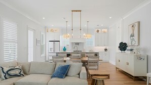 A modern living room with a sofa, dining area, and kitchen in the background. - 66 Parks Edge (Orange Beach)