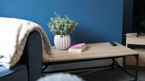 A room with a bed, a small table with a plant and a book, and a remote control on the table. - Central Grimsby House w/ Free Parking & Garden (Grimsby)
