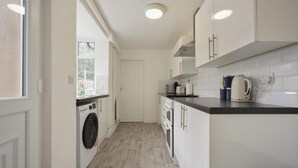 A compact kitchen with a washing machine, a coffee maker, and a kettle on the countertop. - Central Grimsby House w/ Free Parking & Garden (Grimsby)