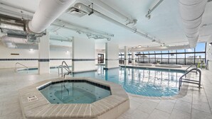 Ein Innenpool mit Whirlpool, einer klaren Decke mit Lüftungskanälen und großen Fenstern für natürliches Licht.