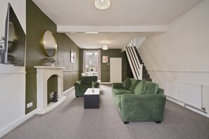 A living room with a green sofa, a white coffee table, and a fireplace.