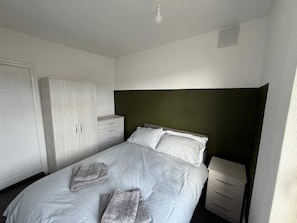 Une chambre à coucher comprenant un lit, une armoire, une table de chevet et une tête de lit.