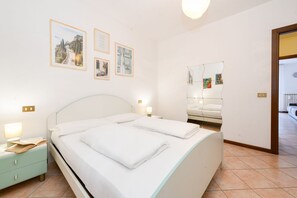 A bedroom with a bed, bedside tables, a nightstand, a mirror, and wall art. - Casa Vuvi - Two-room apartment very close to the beach. (Toscolano Maderno)