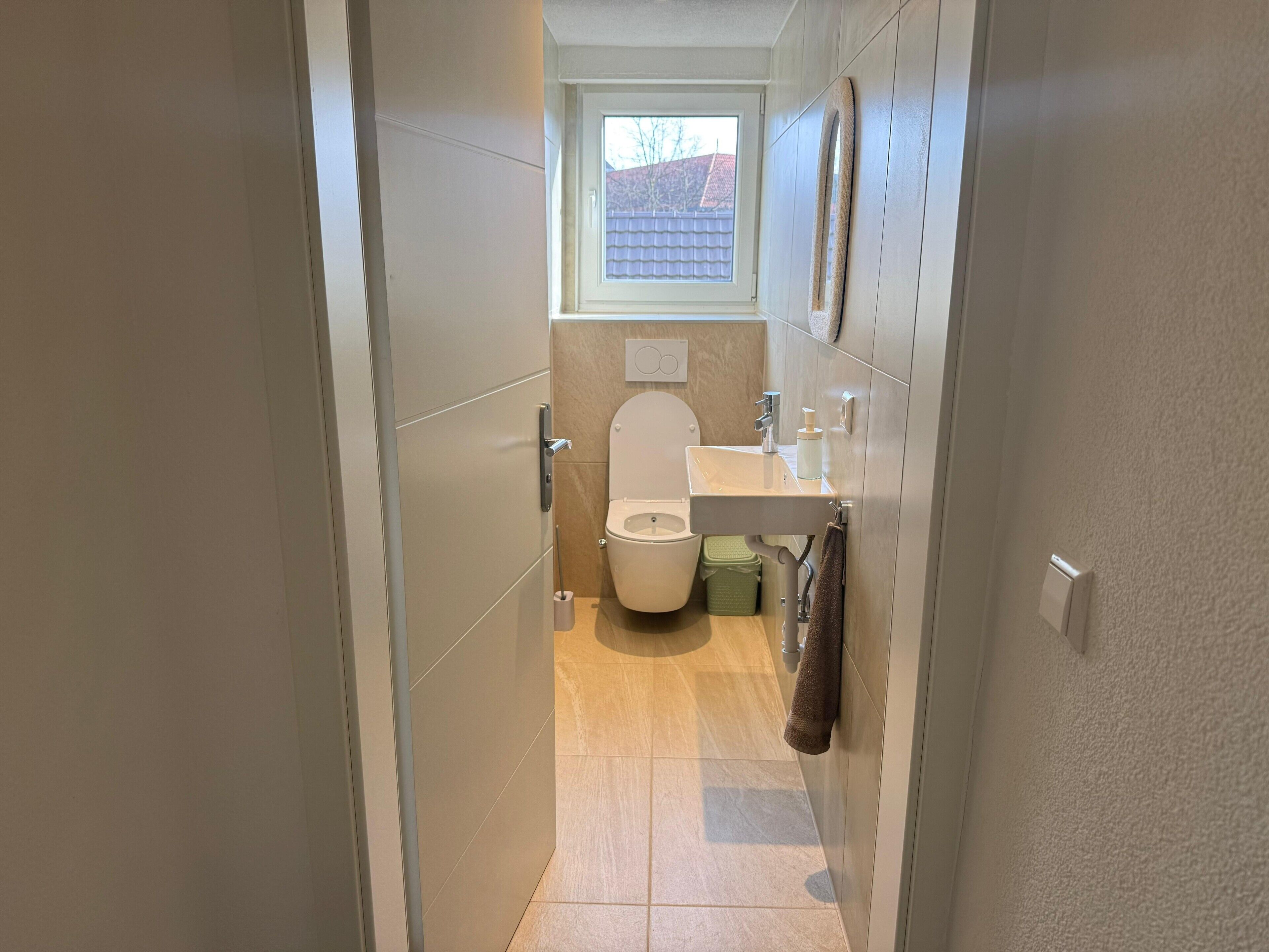 A modern bathroom with a toilet, sink, and window.