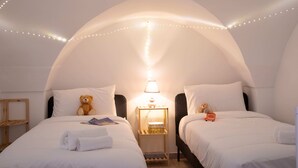 Ein Zimmer mit zwei Betten, einem Nachttisch mit Lampe und Lichterkette.