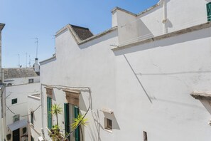 A narrow street with white buildings, green shutters, and a clear blue sky. - Charming Townhouse in Martina Franca Old Town with Roof Terrace (Martina Franca)