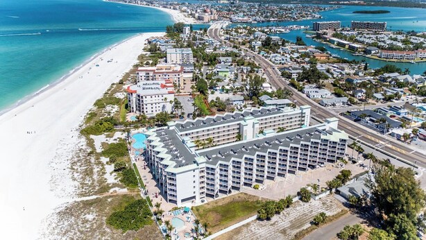 A coastal hotel with a beachfront view, multiple swimming pools, and a parking area. - Sunset Vistas Getaway (Treasure Island)