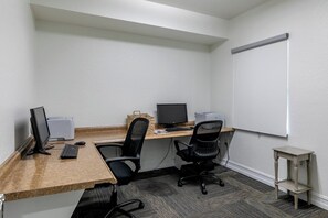 Ein kleiner Büroraum mit zwei Schreibtischen, zwei Stühlen, einer Whiteboard-Tafel und einem kleinen Tisch.