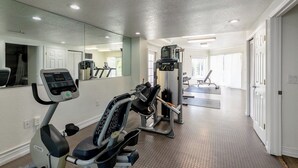 A home gym with exercise equipment, a treadmill, and a mirrored wall. - Sunset Vistas Getaway (Treasure Island)