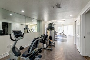 Ein Heimfitnessraum mit Trainingsgeräten, Laufband und einer Spiegelwand.