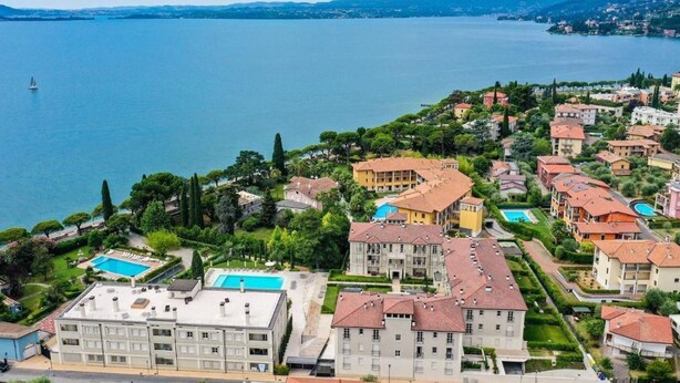A coastal hotel with multiple buildings, a swimming pool, and a view of the sea. - Studio Laura - Corte Fasanella (Toscolano Maderno)