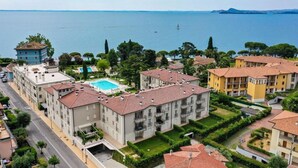 A coastal residential area with apartment buildings, a swimming pool, and a view of the sea. - Studio Laura - Corte Fasanella (Toscolano Maderno)