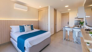 Ein modernes Hotelzimmer mit einem Bett, einem Nachttisch und einer Küchenzeile.