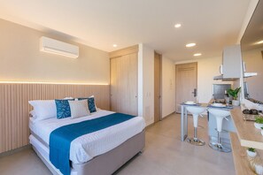 Une chambre d’hôtel moderne équipée d’un lit, d’une table de chevet et d’un coin cuisine.