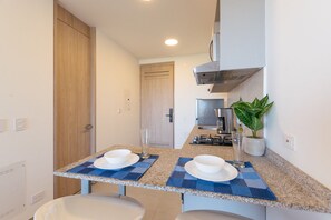 A narrow kitchen with a countertop, a stove, a microwave, and a potted plant. - U-GO Santa Marina Exclusividad y Mar (Santa Marta)