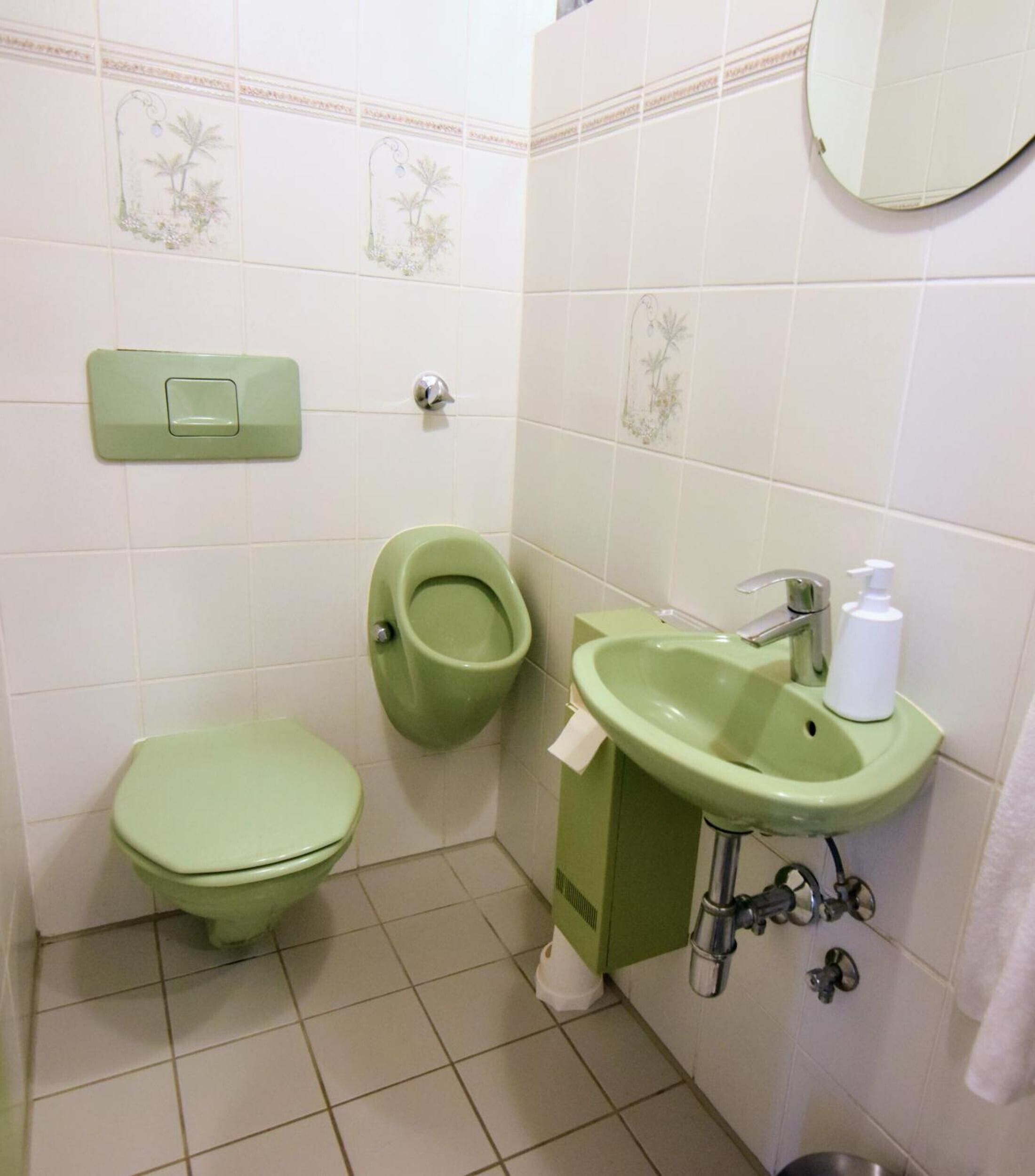Une salle de bain équipée de toilettes, d’un urinoir et d’un lavabo.