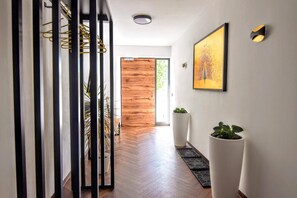 A modern hallway with a wooden door, a framed artwork, and potted plants. - Apartment 'Stilvolle Mit Bauernhof' with Mountain View, Shared Terrace and Wi-Fi (Sankt Martin am Ybbsfelde)