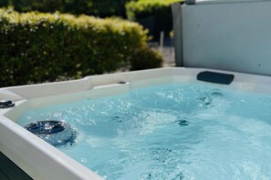 Un bain à remous rempli d’eau, entouré de verdure.