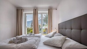 Een slaapkamer met twee bedden, een groot raam en uitzicht op de omgeving.