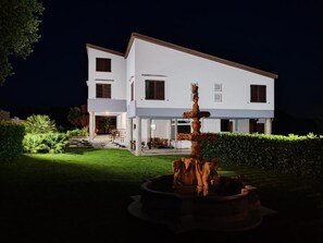 A two-story house with a well-maintained lawn and a central fountain. - Villa Andreina (Amandola)