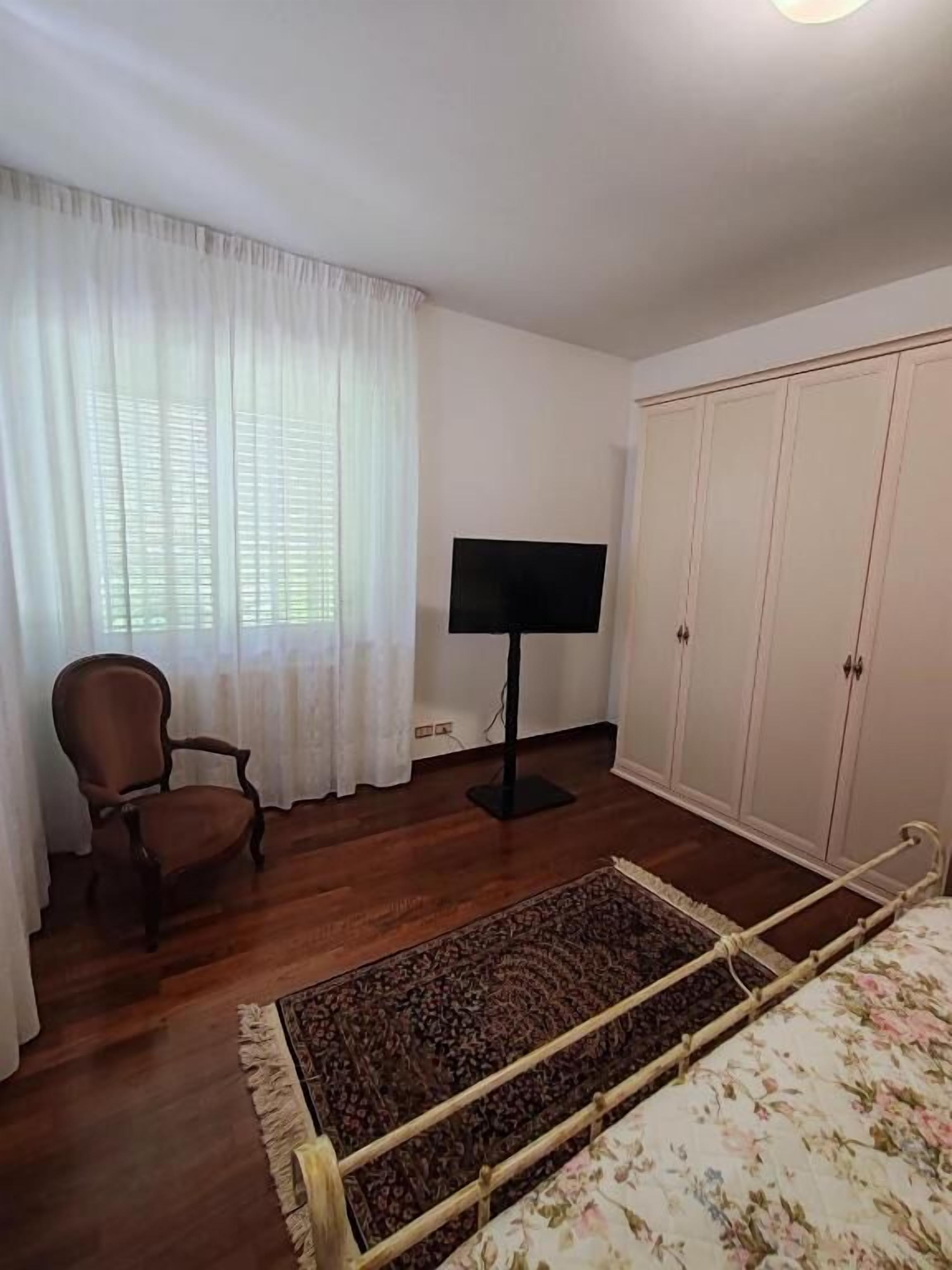 Une chambre à coucher avec un lit, une chaise, une télévision et une armoire.