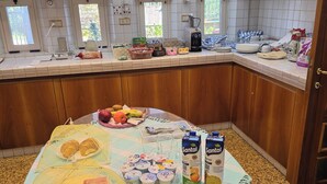 Une cuisine avec une table à manger dressée pour le repas, une machine à café et divers ustensiles de cuisine disposés sur le plan de travail.