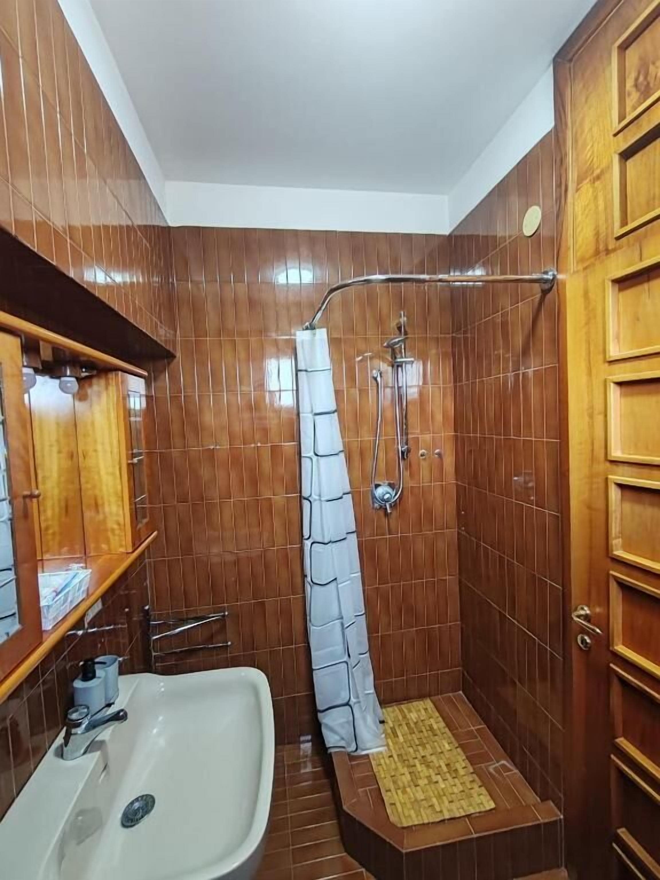 Une salle de bain avec une douche, un lavabo et un lambris en bois.