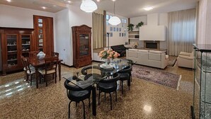 Un salon comprenant une table à manger en verre, un canapé, un téléviseur et une bibliothèque.