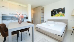 Et moderne hotelværelse med seng, spisebord, stole, et tekøkken og et billede på væggen.