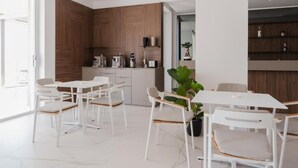 Una cocina moderna con armarios de madera, un comedor con sillas blancas y una planta en maceta.