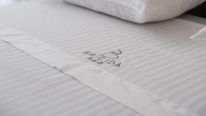 Una cama bien hecha con un almohadón y una colcha con un logo.