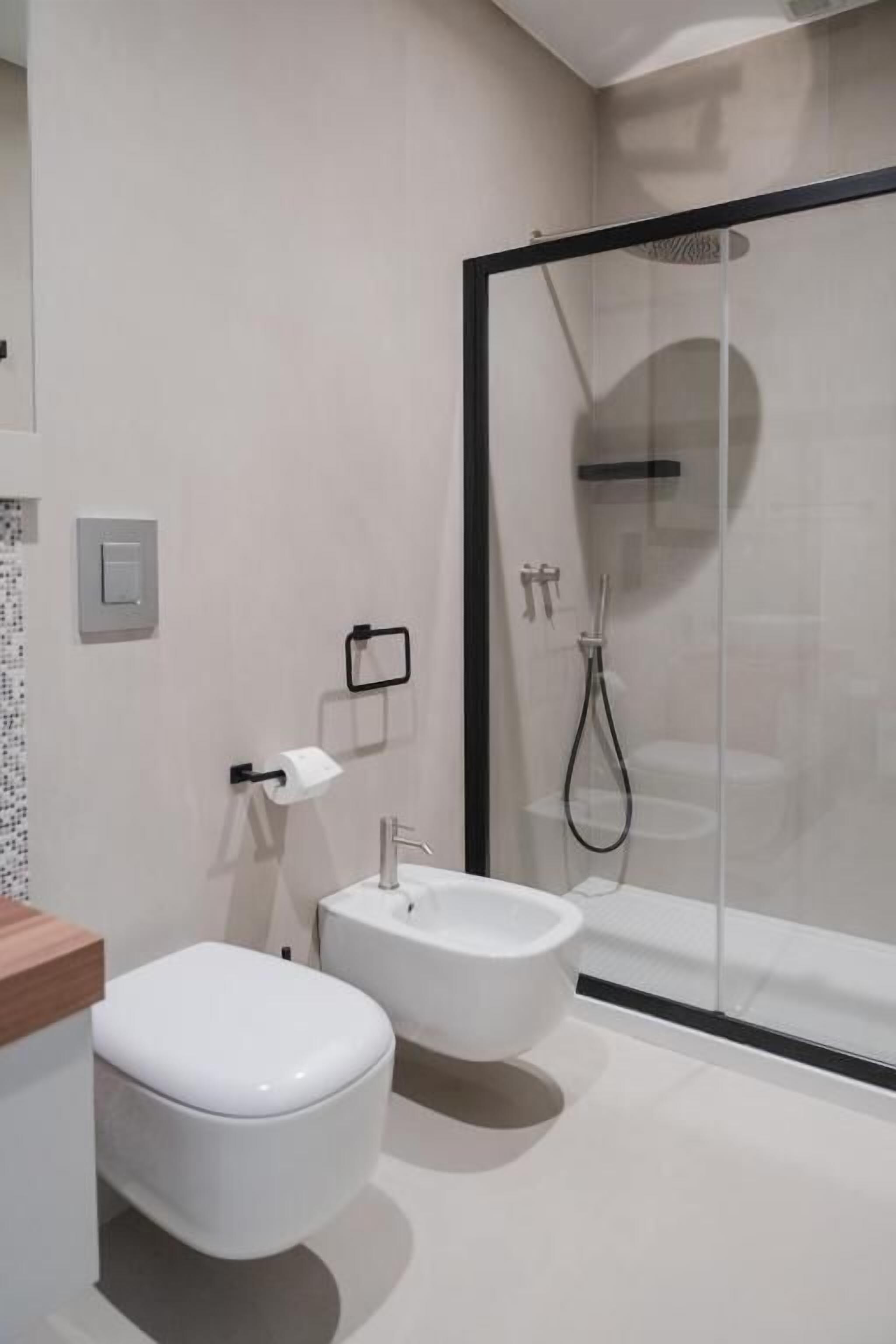 A modern bathroom with a toilet, bidet, and glass-enclosed shower.