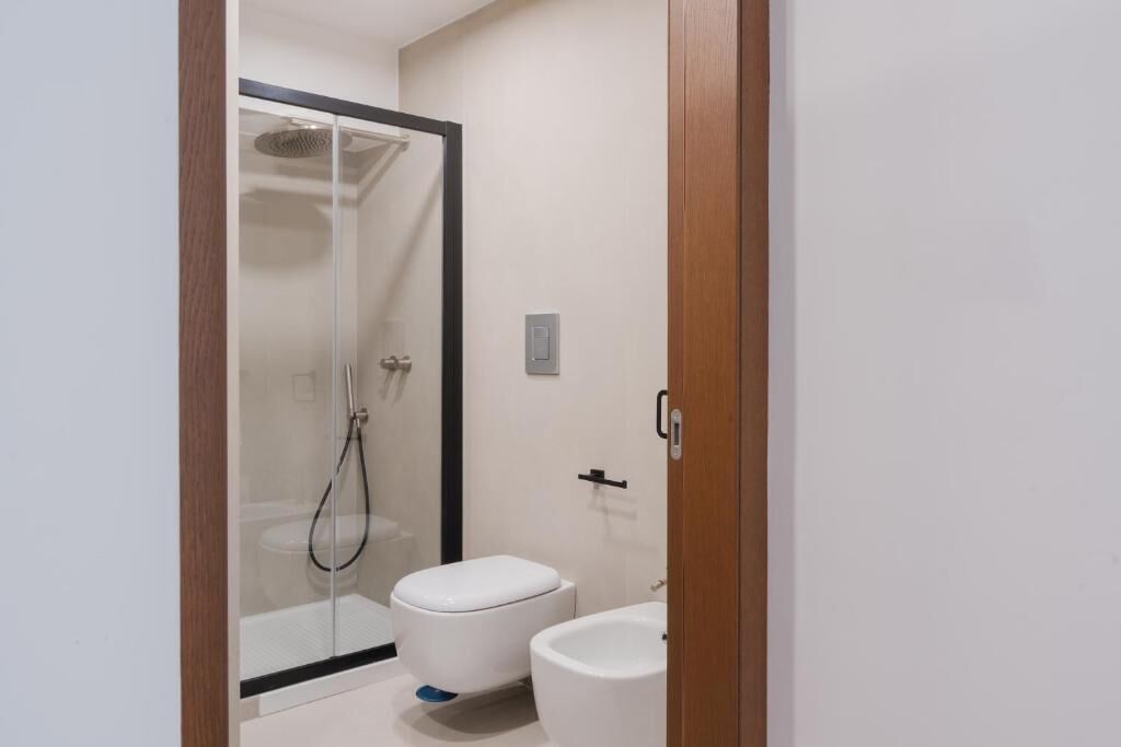 A bathroom with a glass-enclosed shower, a toilet, and a bidet.